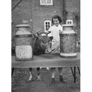  A Woman Standing with Her Cow Between Two Milk Containers 